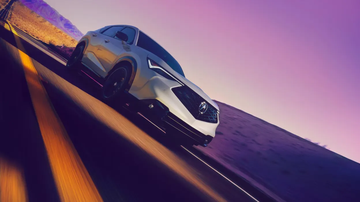 Acura ADX 2026 blanc vu de trois quarts avant en mouvement sur une route au coucher du soleil.