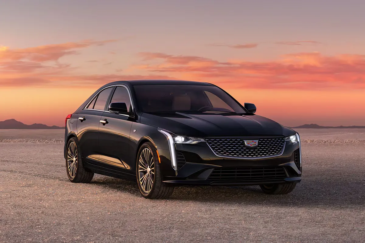 Cadillac CT4 noire vue de trois quarts avant au coucher du soleil, comparée à l’Acura Integra 2026.